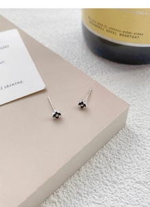 Macro shot of S999 sterling silver flower studs with black zircon petals on beige paper