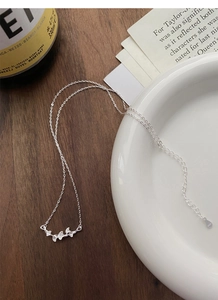 Gros plan du pendentif feuille de ginkgo et marquage S925 sur une chaîne minimaliste
