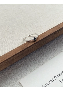 Détail de la bague ajustable en argent S925 avec fleur noire sur tissu à grain texturé