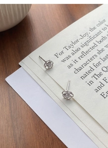 Gros plan de boucles d'oreilles roses en argent avec zircon sur vieux journaux