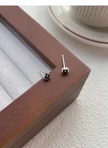 Macro shot of S999 silver ear studs featuring black zircon in a cute animal paw design