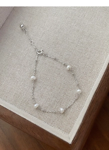 Macro detail of S925 sterling silver chain bracelet with five white freshwater pearls