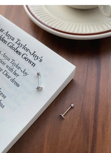 Macro shot of silver clover screw-back earrings on an open book and wooden table