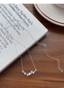 Détail du pendentif feuille de ginkgo en argent S999 avec zircon sur fond décoré