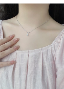 Gros plan d'un collier pendentif goutte d'eau en argent sur un mannequin en haut rose