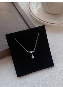 Vue détaillée en macro du pendentif goutte d'argent sur une carte de présentation en velours noir