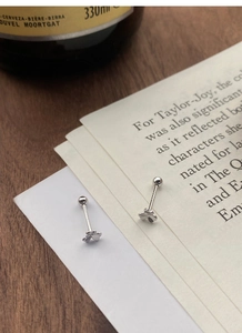 Macro shot of S999 sterling silver clover screw-back earrings on a book background