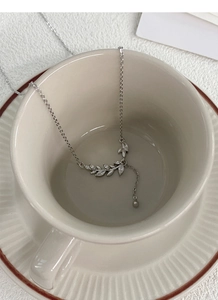 Macro detail of S999 silver wheat ear necklace with zircon inlay in a ceramic cup