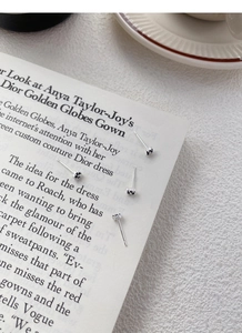 Close-up of four S999 sterling silver black clover stud earrings on a magazine