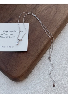 Vue détaillée du pendentif goutte en argent S999 avec zircon sur plateau en bois