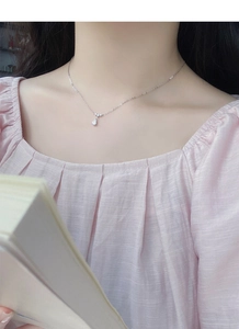 Gros plan du collier à pendentif goutte en argent 999 porté sur un cou de femme