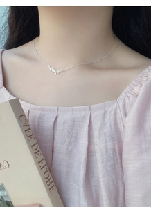 Détail d'un collier pendentif papillon en argent porté par un mannequin sur la clavicule