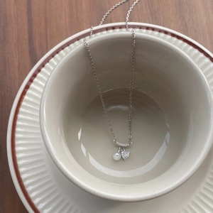 Collier en argent S925 avec pendentif cœur et perle sur une tasse en céramique
