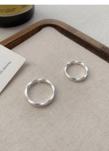 Detail of Mobius strip silver rings with frosted matte finish on rustic linen cloth