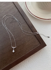 Gros plan du collier goutte en argent S925 avec zircon clair et texture métal raffinée