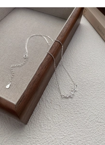 Détail du collier feuille de ginkgo en argent sterling 999 sur plateau bois