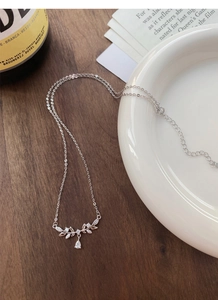 Macro detail of leaf-shaped silver necklace with cubic zirconia and pear-cut stone