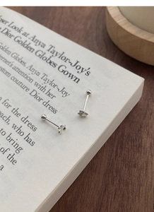 Macro detail of S999 sterling silver clover screw-back stud earrings on a wooden table