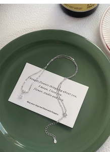 Gros plan d'un collier goutte en argent S925 sur une assiette en céramique vert vintage