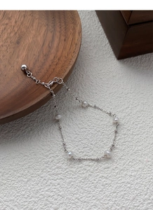 Detail of adjustable S925 silver bracelet featuring natural freshwater pearls on wood
