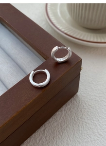 Gros plan de créoles en argent fin S999 mat sur un coffret à bijoux en bois vintage