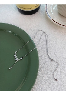 Macro view of S925 sterling silver wheat ear pendant with zircons on green ceramic plate