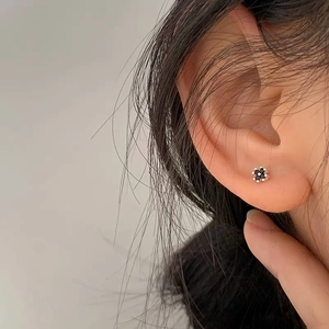 Elegant S999 sterling silver black four-leaf clover stud earrings worn by a model