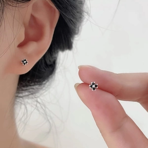 Elegant S999 sterling silver black four-leaf clover stud earrings worn on female earlobe