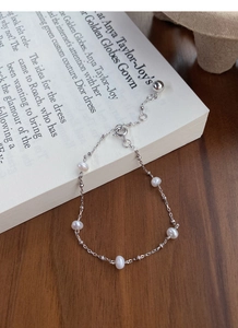 Macro detail of a minimalist S925 silver bracelet with five natural freshwater pearls