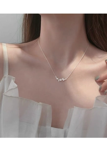 Détail du collier feuille de ginkgo en argent sterling 999 sur le cou d'une femme