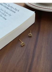 Détail macro de boucles d'oreilles cœur dorées avec logo G entrelacé sur table bois
