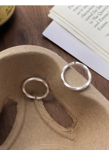 Detail of adjustable S999 silver Mobius rings with a matte frosted finish on a desk