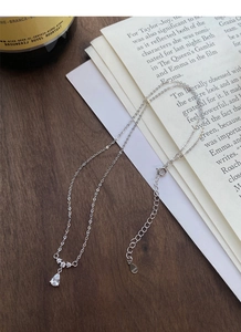 Détail du collier goutte en argent sterling S925 avec cristaux sur fond de livre vintage