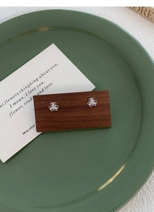 Close-up of S999 silver clover stud earrings with sparkling cubic zirconia on wood