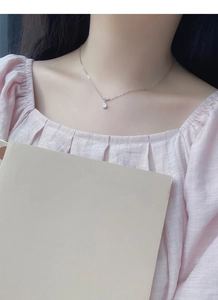 Gros plan d'un collier en argent massif avec pendentif goutte porté par une femme