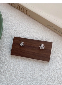 Macro shot of clover-shaped S999 silver earrings with teardrop cubic zirconia inlay