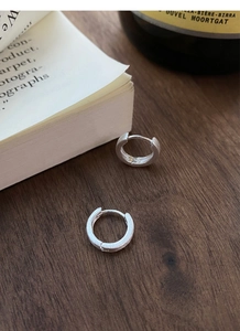 Gros plan détaillé des boucles d'oreilles en argent S999 mat sur un bureau en bois
