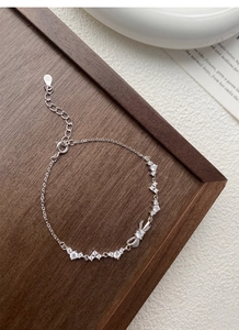 Macro shot of S925 silver bracelet featuring a bow charm and sparkling zircon stones