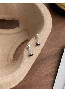 Détail macro de boucles d'oreilles argentées à vis avec émail noir sur un plateau texturé
