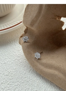 Macro shot of S999 sterling silver snowflake earrings with sparkling zircon on a stand