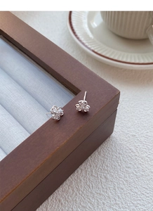 Macro shot of clover earrings with pear-shaped stones on a wooden jewelry box