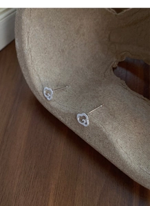Gros plan de boucles d'oreilles en argent en forme de nuage sur un support en papier brun
