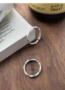 Macro detail of silver Mobius rings with matte texture on a rustic wooden table background