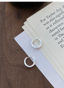 Gros plan sur des boucles d'oreilles créoles en argent S999 brossé sur papier vintage