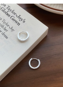 Détail de boucles d'oreilles en argent S999 mat avec texture brossée sur bois