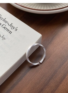 Detail of adjustable Mobius ring with matte brushed finish on a vintage book surface
