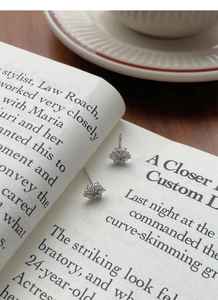 Detailed view of silver snowflake stud earrings with cubic zirconia on a book page