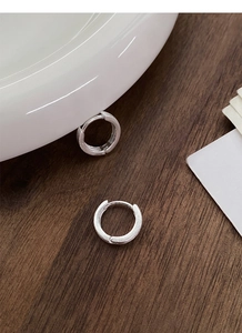 Gros plan de créoles en argent sterling S999 avec texture mate brossée sur bois sombre