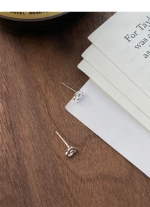 Gros plan sur les boucles d'oreilles GG en argent poli sur une surface en bois vintage