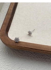 Close-up of S999 silver snowflake earrings with sparkling zircons on a wooden tray